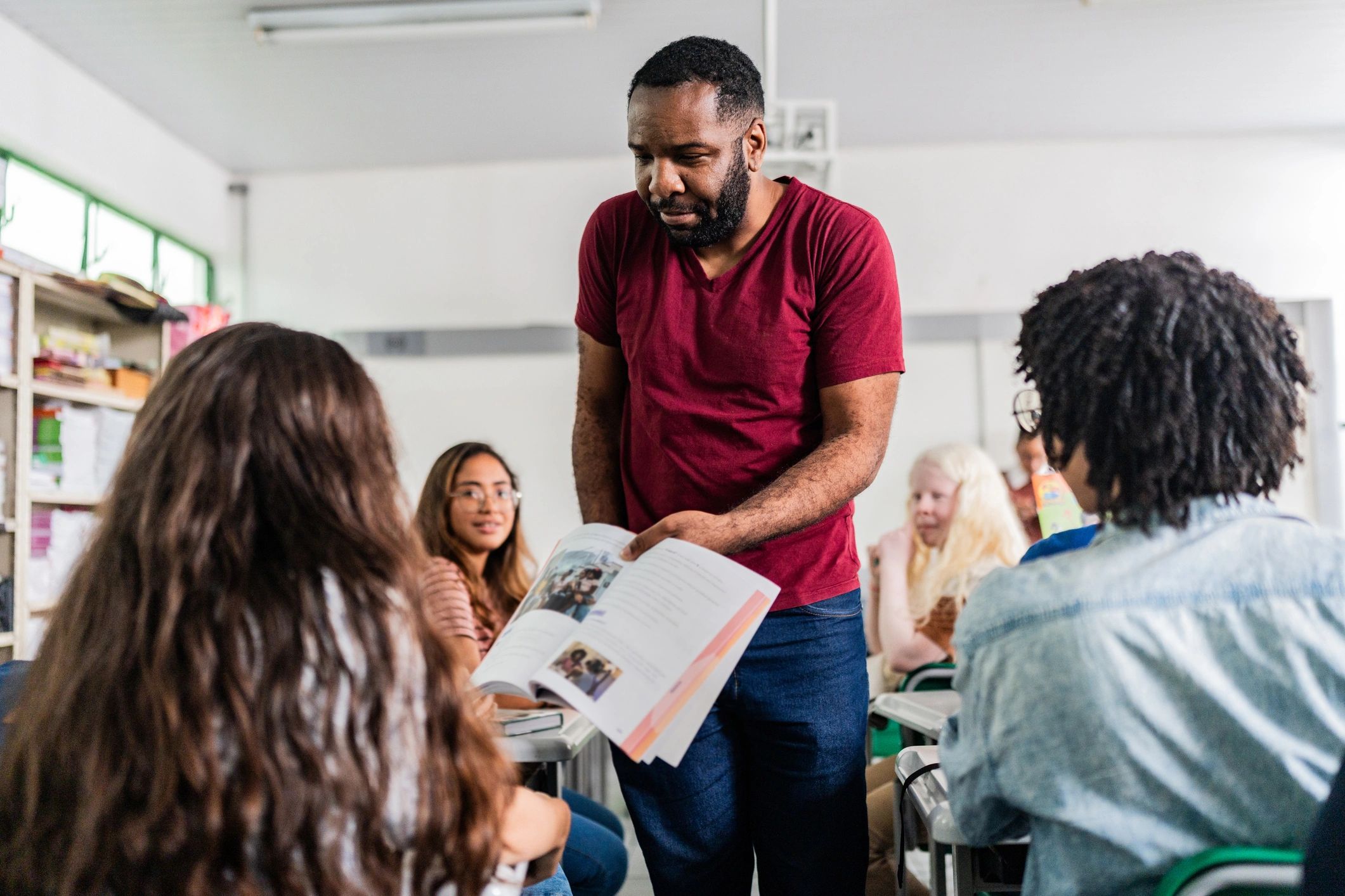 Teacher presenting textbook content to diverse class in classroom